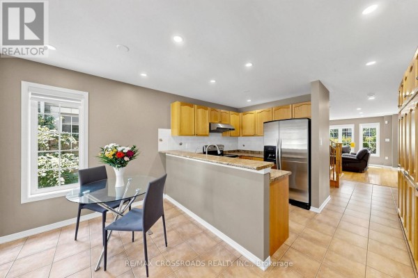 Kitchen and dining area with light brown cabinets, granite countertops, and a stainless steel refrigerator. - 41 Prince Charles Way, Markham