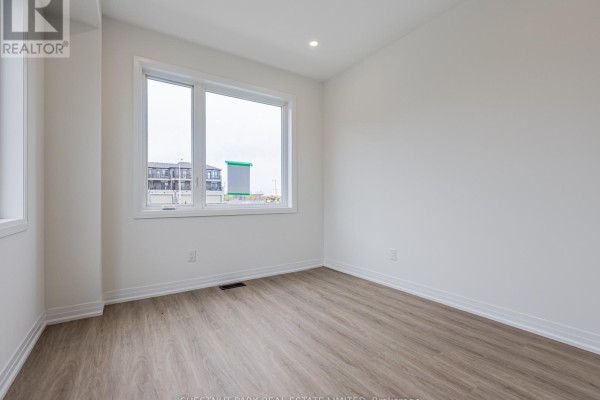 Empty room with light wood floors and a large window overlooking the neighborhood. - 41 Robert Eaton Avenue, Markham