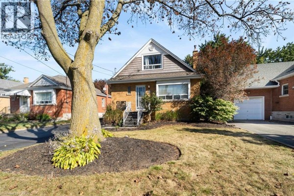 A large tree in the foreground partially obscures the front of the yellow brick bungalow. - 41 Sharon Avenue Unit# Main Floor, Hamilton