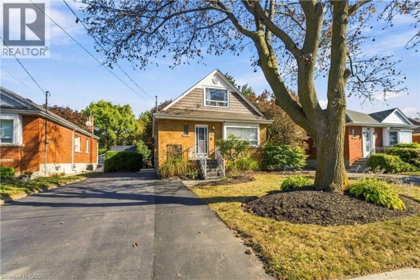 Side view of the yellow brick bungalow showing a driveway and neighbouring properties. - 41 Sharon Avenue Unit# Main Floor, Hamilton