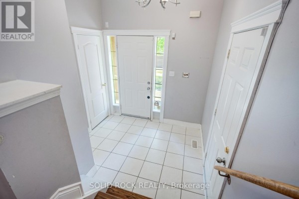 Interior entryway with white tile flooring, white doors, and a staircase leading upwards. - 41 Trumpet Valley Boulevard, Brampton