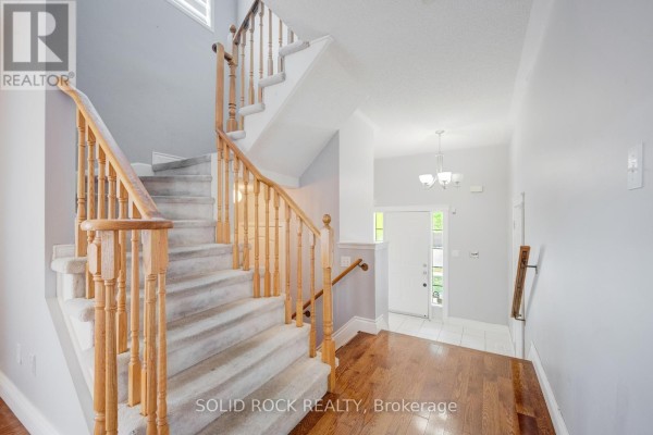 View of a carpeted staircase with wooden railings and hardwood flooring at the bottom. - 41 Trumpet Valley Boulevard, Brampton