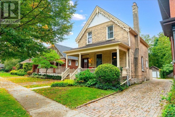 Side exterior view of a two-story brick house with a covered porch, driveway, and mature trees. - 41 Victor Street, London South
