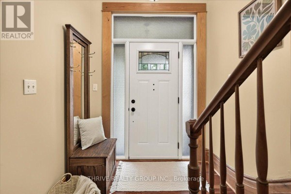 Interior entryway with a white door, wood bench with storage, mirror, and staircase railing. - 41 Victor Street, London South