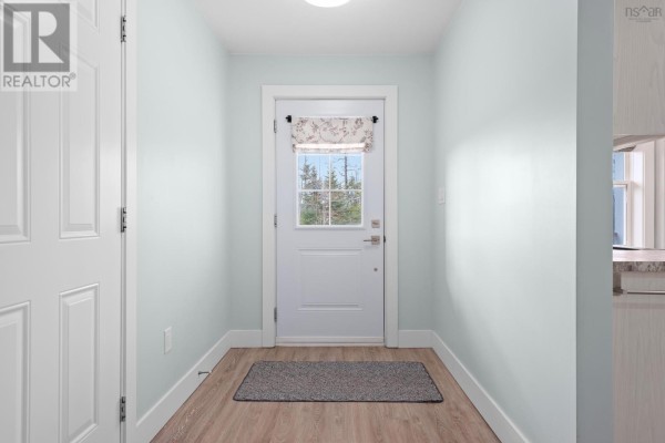 Interior view of a hallway with a back door and a mat on the wood-look floor. - 41 Wineberry Way, Upper Sackville
