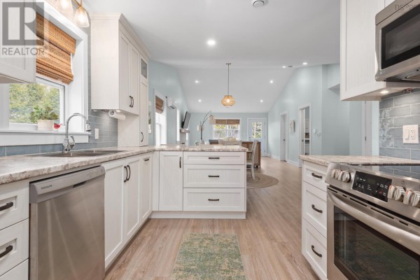 View of the kitchen and open-concept living area from the right side, showing white cabinets and appliances. - 41 Wineberry Way, Upper Sackville