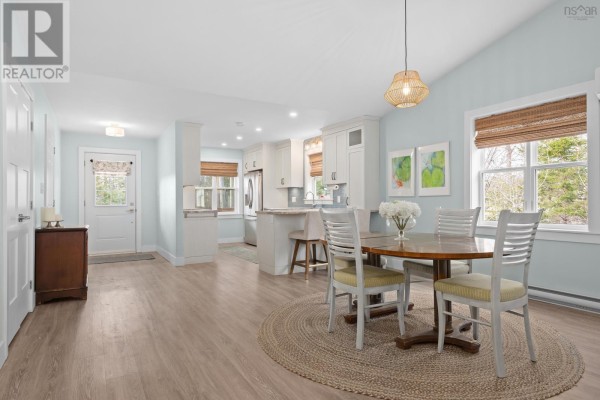Open-concept dining area and kitchen with a round table, chairs, and a view of the back door. - 41 Wineberry Way, Upper Sackville