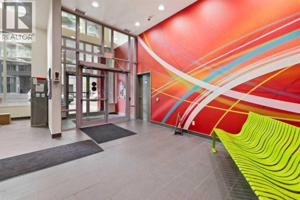 Building lobby with glass doors, grey tiled floor, and a vibrant red abstract mural. - 410, 10 Brentwood Common Nw, Calgary