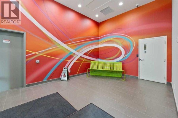 Apartment building lobby featuring a bright red mural with colorful lines and a green bench. - 410, 10 Brentwood Common Nw, Calgary