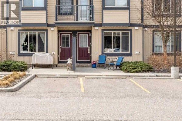 Ground level view of townhouse entrance doors with adjacent windows and parking spaces. - 410, 121 Copperpond Common Se, Calgary