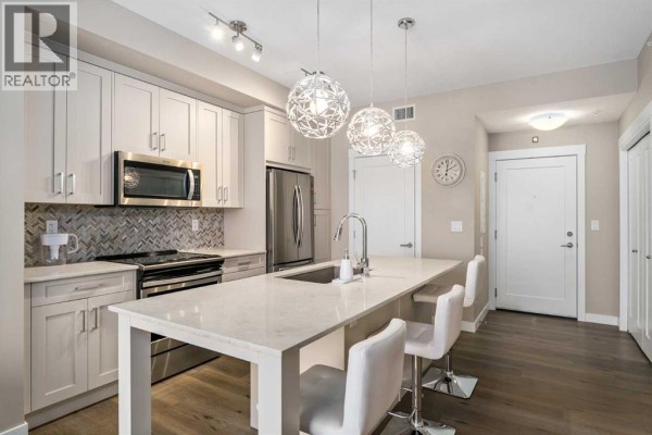 Kitchen with light gray cabinets, quartz countertops, and stainless steel appliances. - 410, 35 Walgrove Walk Se, Calgary