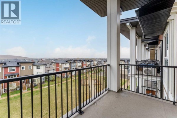 Balcony with a view of multi-colored townhouses and a grassy area. - 410, 35 Walgrove Walk Se, Calgary
