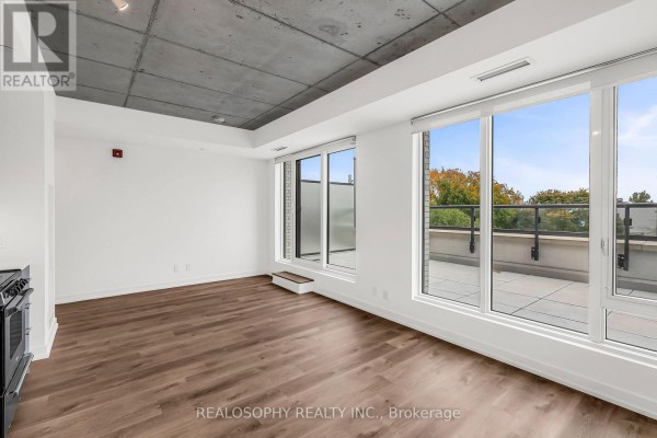 Living area with large windows, balcony access, and exposed concrete ceilings. - 410 - 115 Larchmount Avenue, Toronto