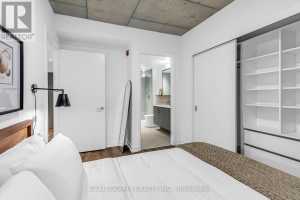 Bedroom with a large closet, ensuite bathroom entrance, and a full-length mirror. - 410 - 115 Larchmount Avenue, Toronto