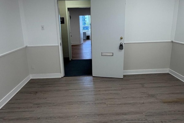 Interior view of an empty office space with gray wood flooring and a white door. - 410 - 170 The Donway West, Toronto
