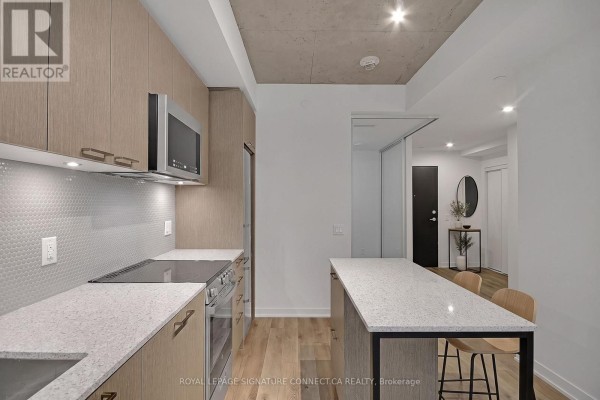 Looking through frosted glass doors into a hallway with white doors and wood floors. - 410 - 1808 St Clair Avenue, Toronto