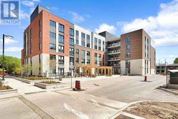 Exterior view of a modern brick and metal apartment building with balconies and entrance pergola. - 410 - 385 Hill Street, London East