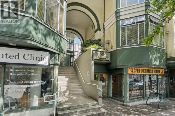 Building entrance with stairs leading up past commercial storefronts and under an archway. - 410 3727 W 10th Avenue, Vancouver