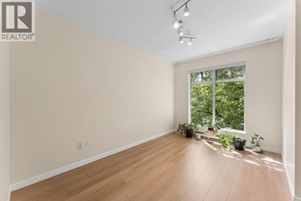 Empty room with light beige walls, light wood flooring, and a large window. - 410 3727 W 10th Avenue, Vancouver