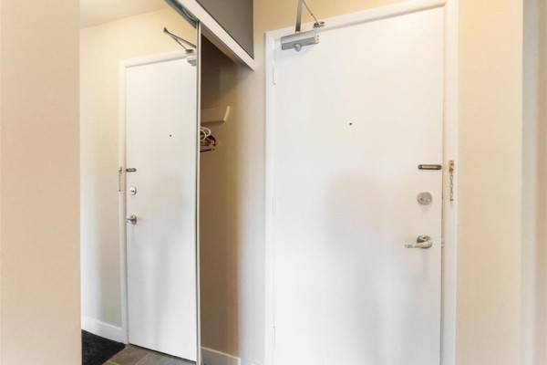 Two white apartment doors in a hallway. One is a closet door with mirrored panels. - 410 565 Corydon Avenue, Winnipeg