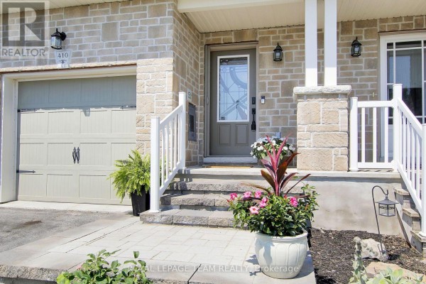 Detail of townhouse entrance steps and garage door with landscaping and potted plants. - 410 Ann Street, Mississippi Mills