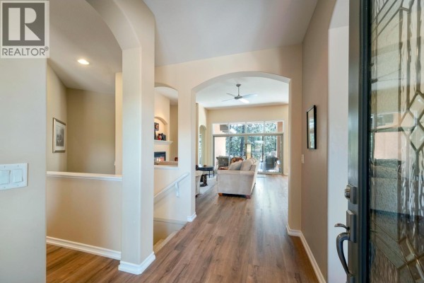 Interior entryway hallway with wood-look flooring, arched doorways, and stairs leading to the main floor. - 4100 Gallaghers Parkland Drive Unit# 16, Kelowna