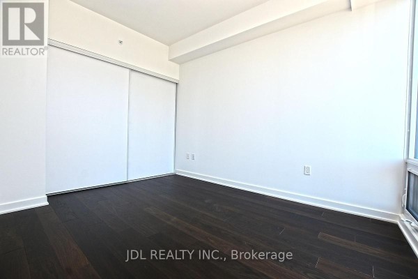 Empty room with dark wood floors and large sliding closet doors. - 4101 - 115 Blue Jays Way, Toronto