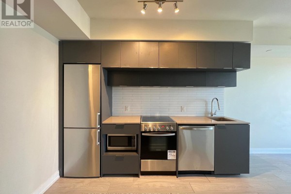 Modern kitchen with dark grey cabinets, stainless steel appliances, and white subway tile backsplash. - 4101 - 181 Dundas Street E, Toronto