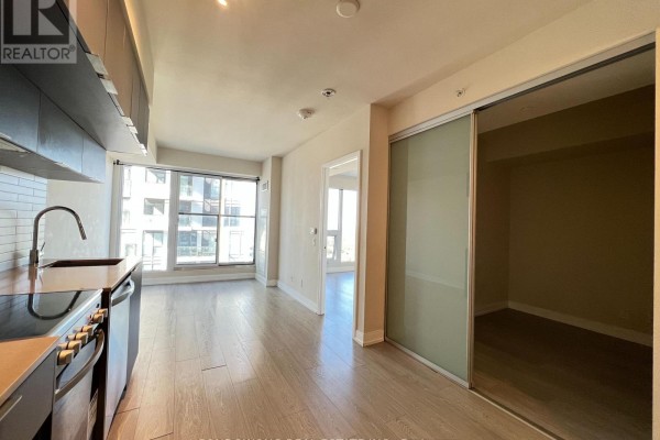 Living area with light wood floors, large window, and mirrored sliding closet doors. - 4101 - 181 Dundas Street E, Toronto