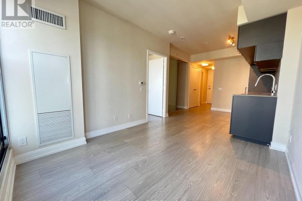 Interior view from the living area, showing a hallway with doors and a modern kitchen. - 4101 - 181 Dundas Street E, Toronto