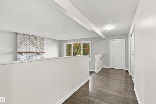 Interior hallway with gray walls, white trim, dark wood floors, and a white partition wall. - 4102 48 Street, Bonnyville Town