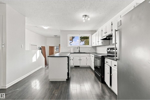 Kitchen with white cabinets, black granite countertops, white subway tile backsplash, and a central island. - 4102 48 Street, Bonnyville Town