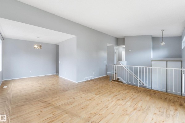 Open concept living and dining area with light wood floors, gray walls, and two chandeliers. - 4105 44 Av, Stony Plain