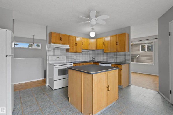 Kitchen with light wood cabinets, white appliances, a small island, and tiled floors. - 4105 44 Av, Stony Plain