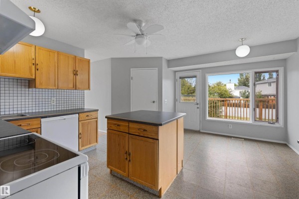 Kitchen with a doorway to the backyard, a small island, and a window overlooking the deck. - 4105 44 Av, Stony Plain