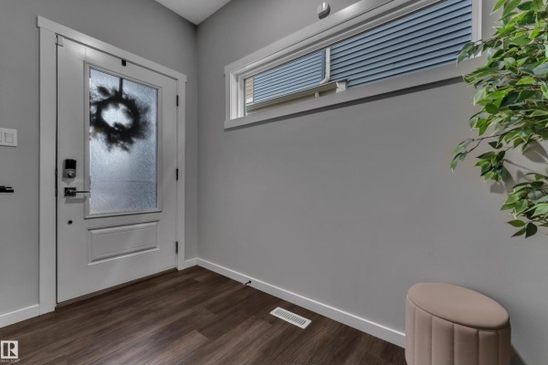 Interior entryway with a glass door, grey walls, and dark wood flooring. - 4107 5 Av Sw, Edmonton