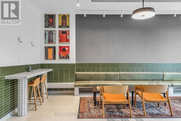 Lobby seating area with green tile accent wall, wooden chairs, and a patterned rug. - 411 - 115 Larchmount Avenue, Toronto