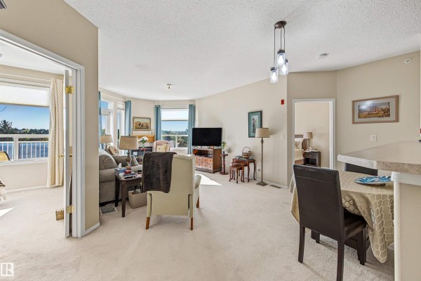 Living room with beige carpet, large windows, balcony door, and furniture. - #411 10 Ironwood Pt, St  Albert