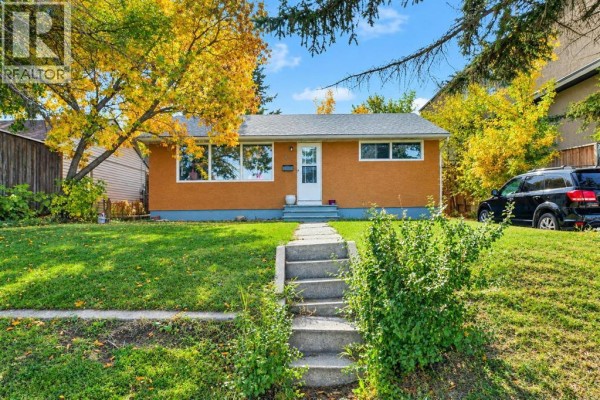 Front view of the home with a lawn, walkway, and parked car. - 411 33 Avenue Ne, Calgary