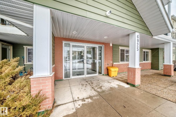 Exterior of apartment building with green siding and snow on the ground. - #411 6925 199 St Nw Nw, Edmonton