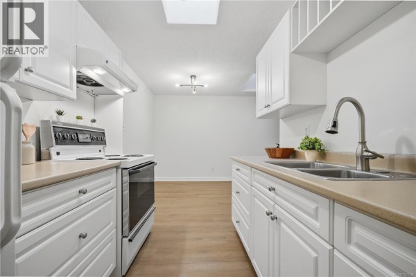 White galley kitchen with beige countertops, double sink, stainless steel faucet, and white appliances. - 411 909 Pembroke St, Victoria