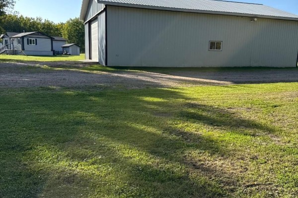 Side view of a large metal barn with a small window, with a mobile home visible in the background. - 41102 Township Road 620, Rural Bonnyville M D 