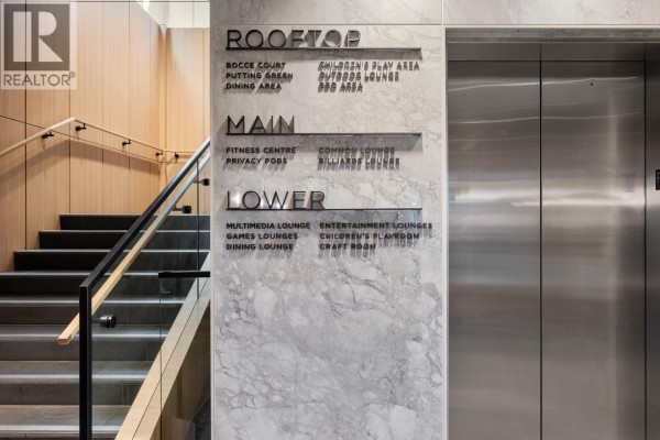 Interior shot showing a marble wall with directory signage and a metal elevator. - 4111 3833 Evergreen Place, Burnaby
