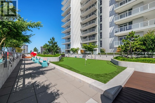 Rooftop amenity area with a putting green, seating, and landscaping, overlooking the city. - 4111 3833 Evergreen Place, Burnaby