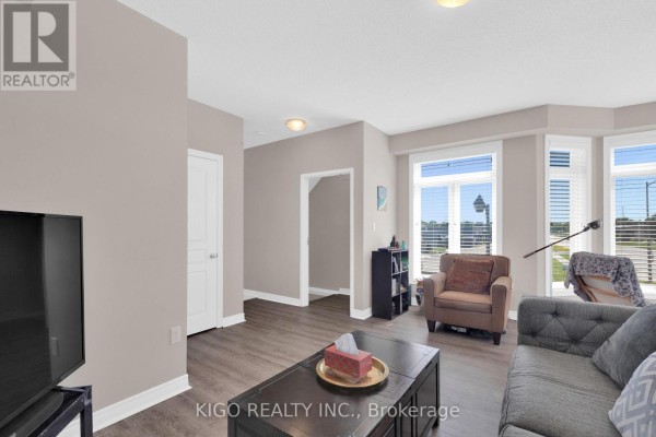 Spacious living room with light carpet, grey sofa, armchair, and multiple large windows. - 4119 Palermo Common, Burlington
