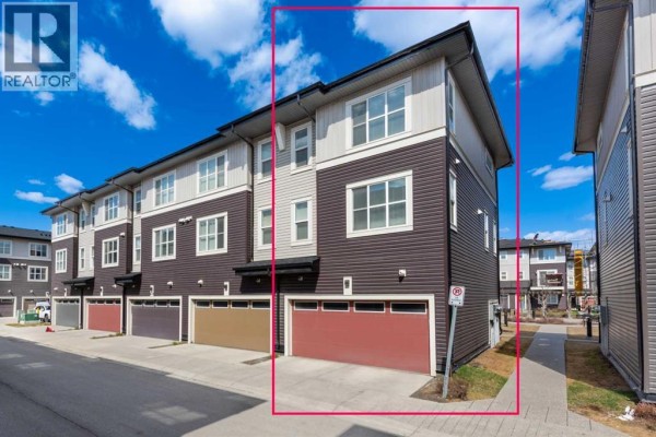 Open-concept kitchen with a white island, stainless steel appliances, and pendant lights overlooking living area. - 412, 30 Cornerstone Manor Ne, Calgary