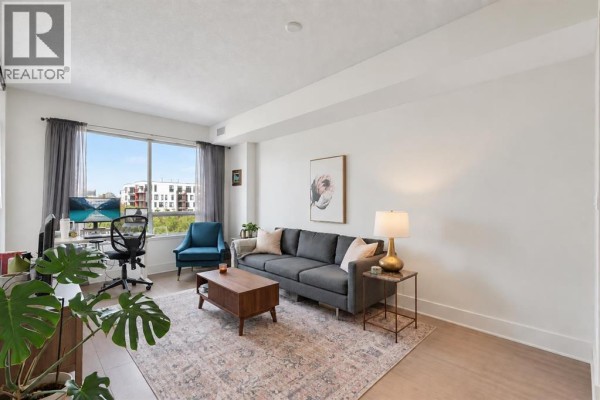 Building lobby with gray sofas, chairs, large windows, and potted plants. - 412, 38 9 Street Ne, Calgary