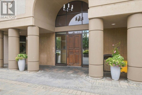A view of the apartment building from the side, surrounded by trees and greenery. - 412 - 220 Forum Drive, Mississauga