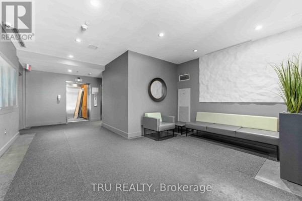 Modern kitchen with dark blue cabinets, stainless steel appliances, and a large island with seating. - 412 - 383 Cumberland Street, Ottawa