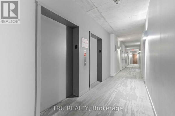 Open concept living and kitchen area with a sofa, dining table, and kitchen island with bar stools. - 412 - 383 Cumberland Street, Ottawa